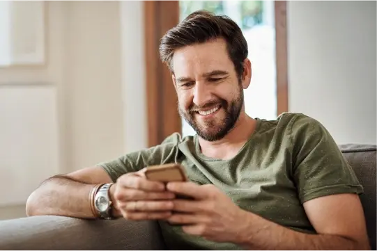 Man smiling while using his mobile phone