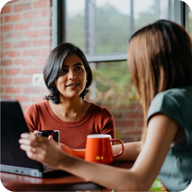 Two women chatting with a laptop and having a coffee