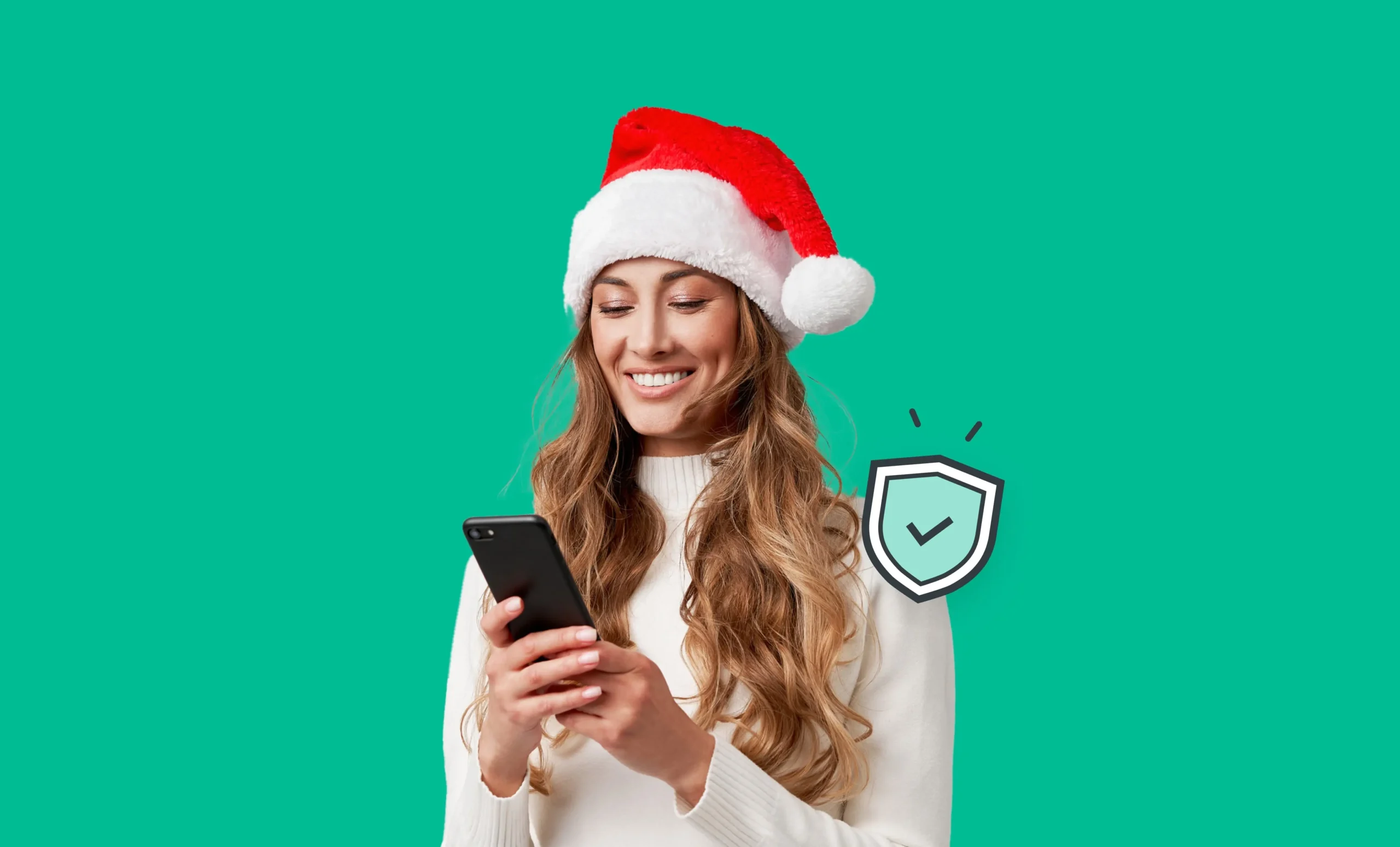 An image of a woman wearing a Santa hat and smiling at her phone.