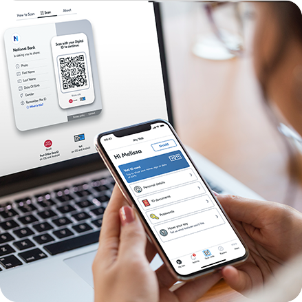 Melissa looking at Yoti ID homepage on her mobile while she prepares to share identity details with an organisation by using the Yoti QRCode displayed on her laptop